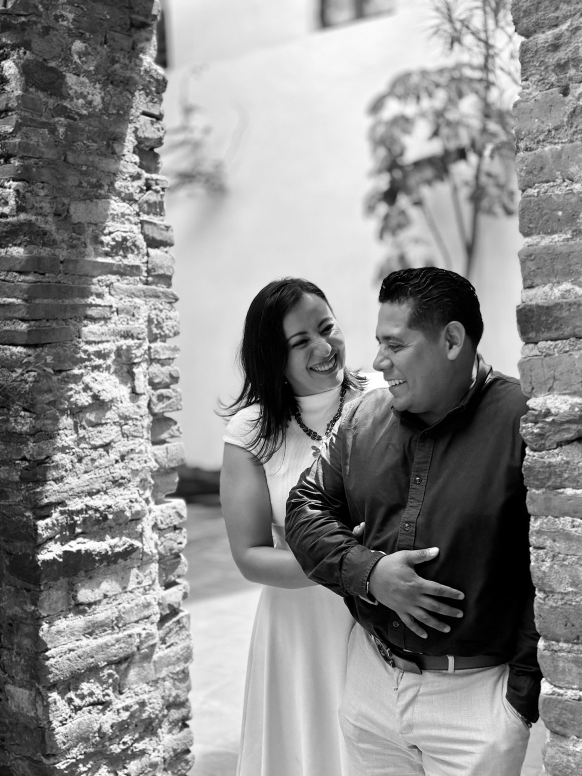 Ofelia y Alberto sonriendo entre muros de piedra, en blanco y negro