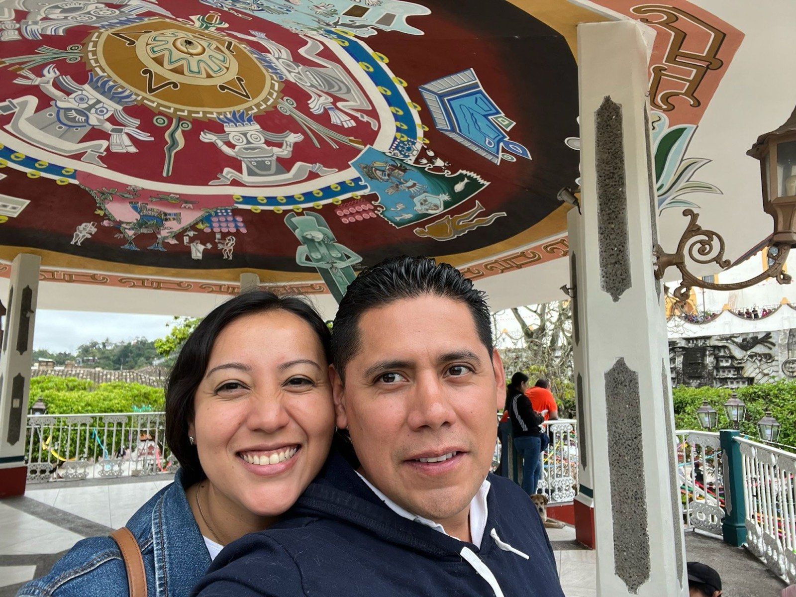 Ofelia y Alberto abrazados bajo un kiosco con mural